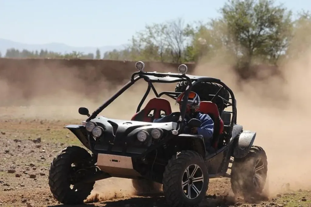 Two-seat off-road buggy driving a sandy desert trail near Agadir with dust trailing behind