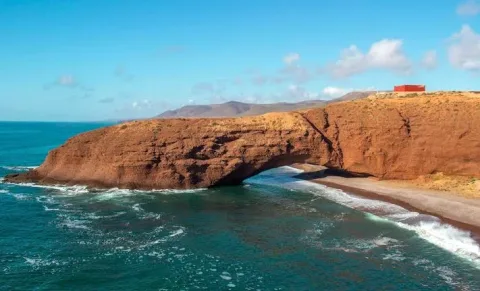 Red sandstone sea arch at Legzira beach rising over the turquoise Atlantic