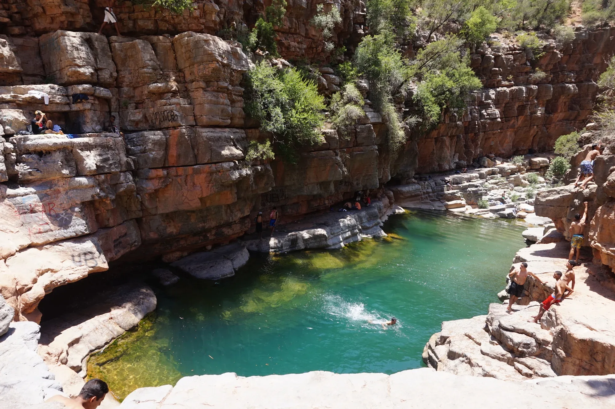 Swimmer diving into a turquoise rock pool between smooth rocks in Paradise Valley near Agadir