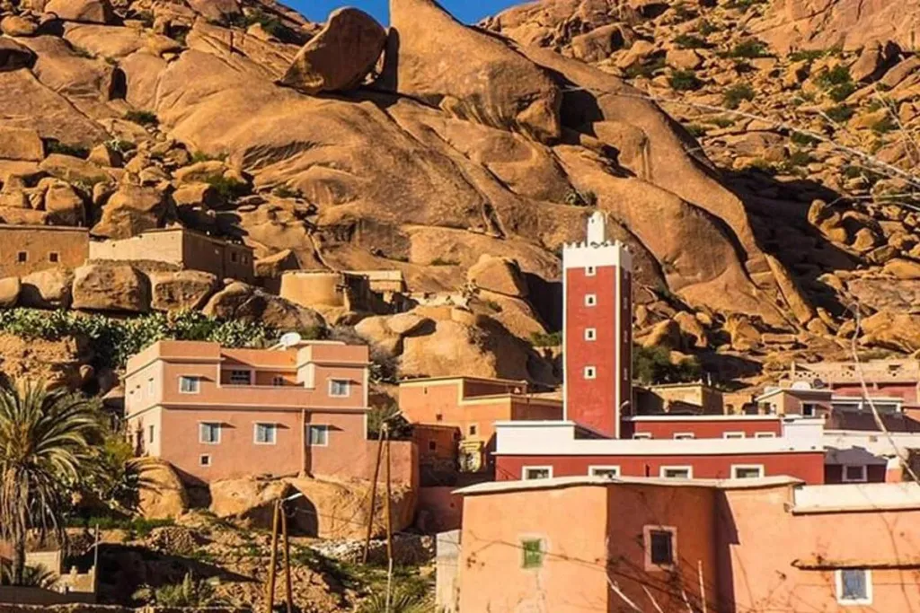 Village houses and a red minaret nestled beneath giant granite rock formations in Tafraoute
